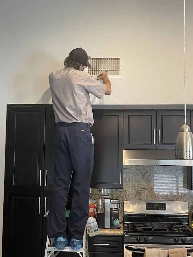 Technician inspecting an air vent during HVAC service in PiÃ±on Hills